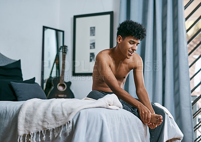 Buy stock photo Shot of a young man massaging his foot in the morning after waking up at home