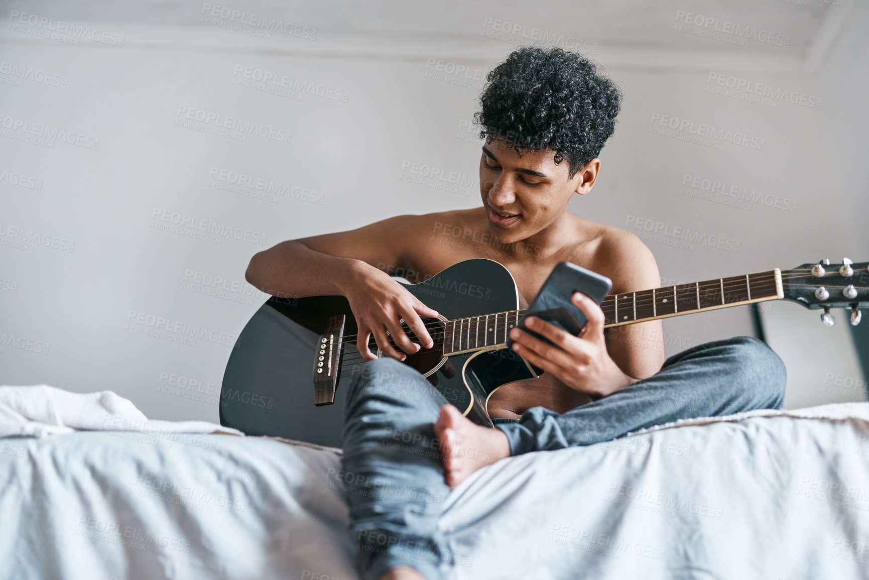 Buy stock photo Guitar, bed and man in home playing music for learning chords, tuning or songwriting with creativity. Artist, acoustic instrument and male person relaxing in bedroom with strings for jam session.