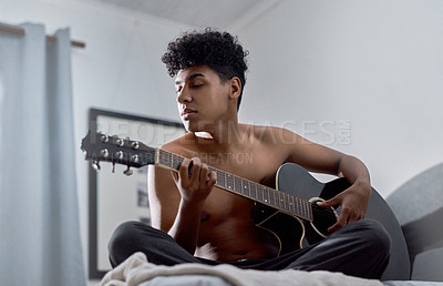 Buy stock photo Shot of a young man playing the guitar in his bedroom at home