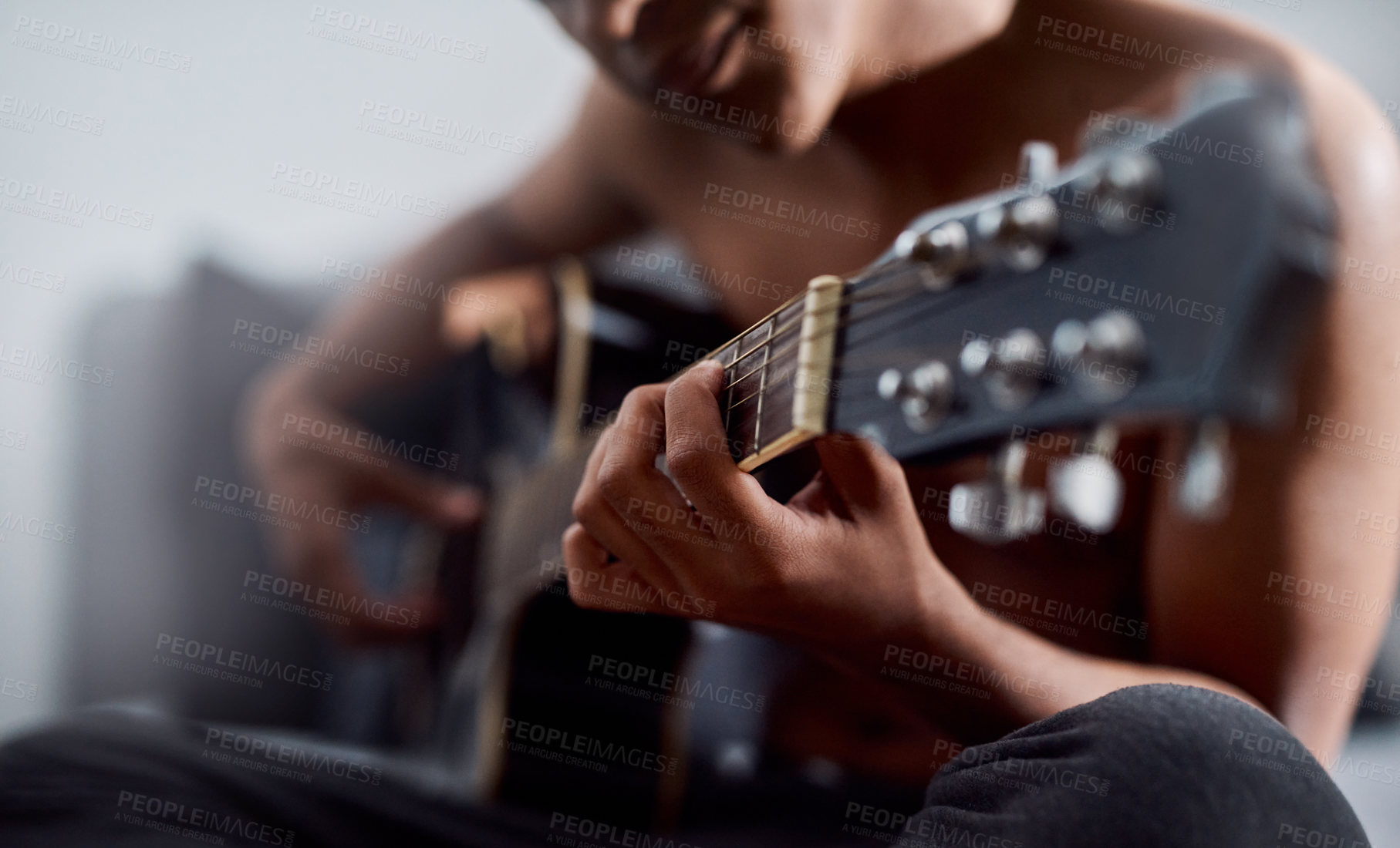 Buy stock photo Cropped shot of a young man playing the guitar in his bedroom at home