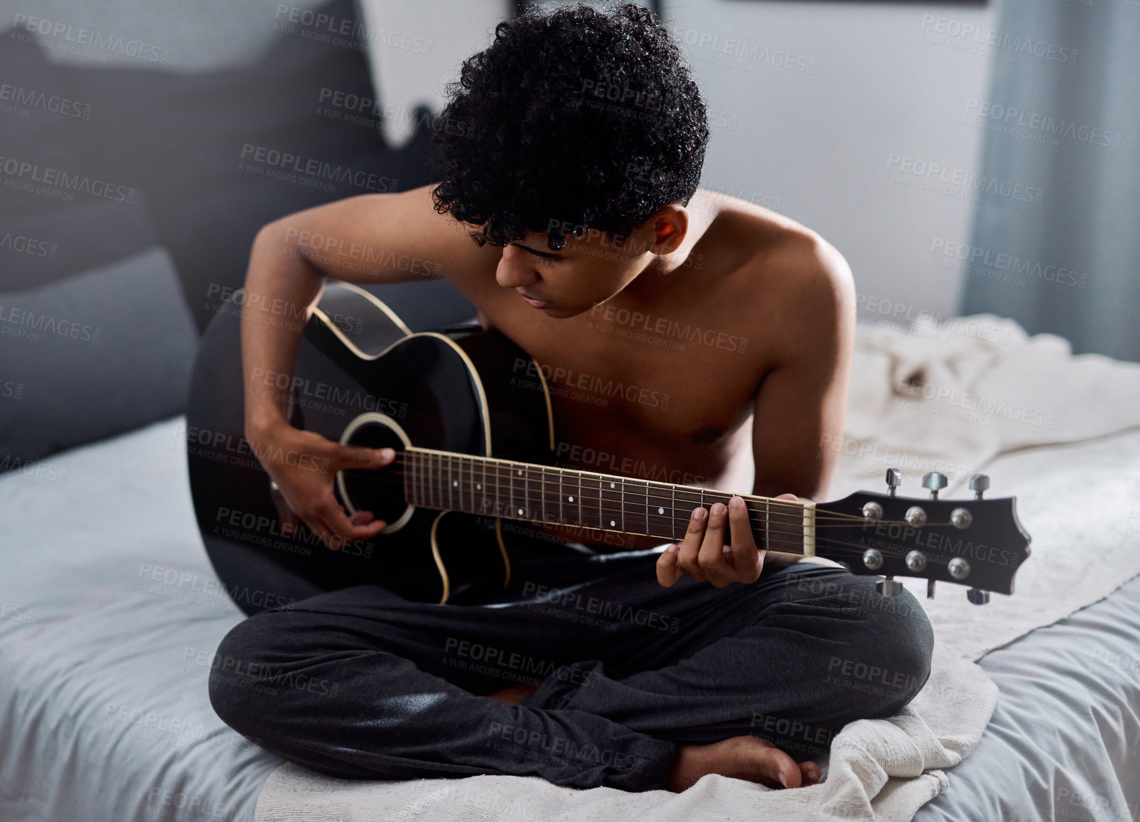 Buy stock photo Shot of a young man playing the guitar in his bedroom at home