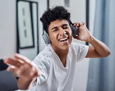 Buy stock photo Shot of a young man using headphones to listen to music at home