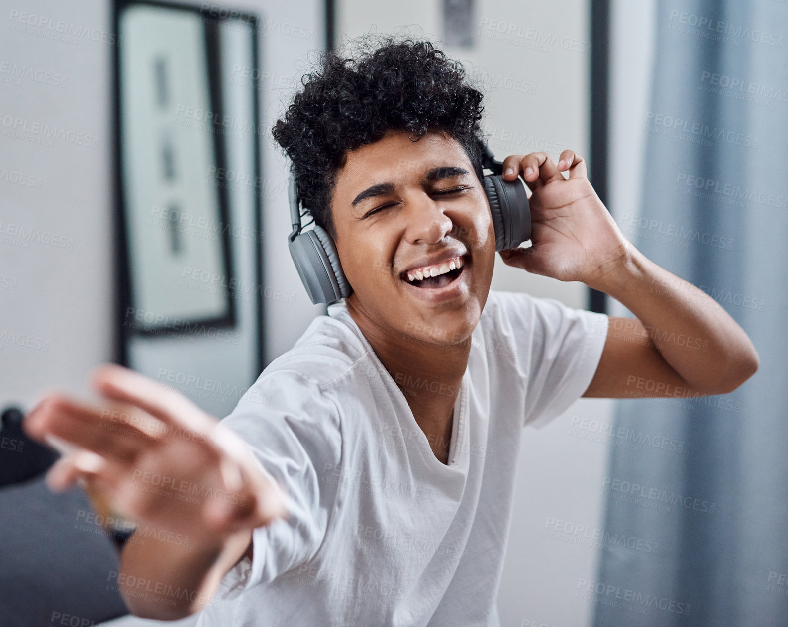 Buy stock photo Shot of a young man using headphones to listen to music at home