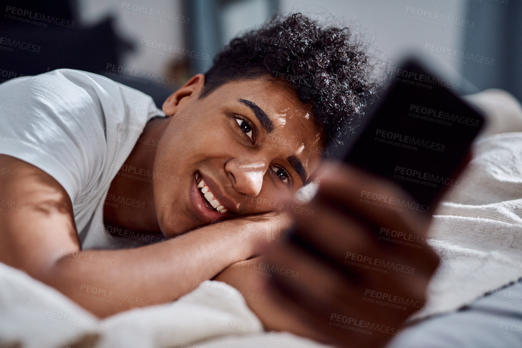 Buy stock photo Teenager, happy and communication on bed with phone for social media, connection and weekend break. Male person, smile and comfort in home with mobile conversation for internet, web and streaming