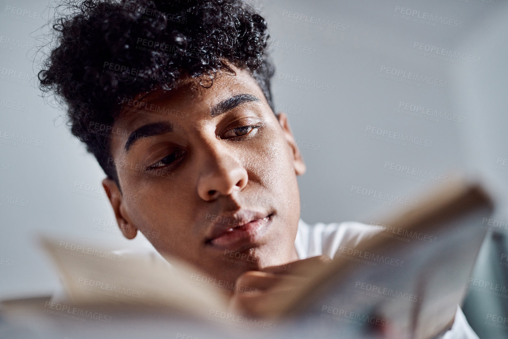 Buy stock photo Book, face and reading with teen boy on bed in home for weekend education, literature or study. Hobby, relax or storytelling with person in bedroom of apartment for development, growth or learning