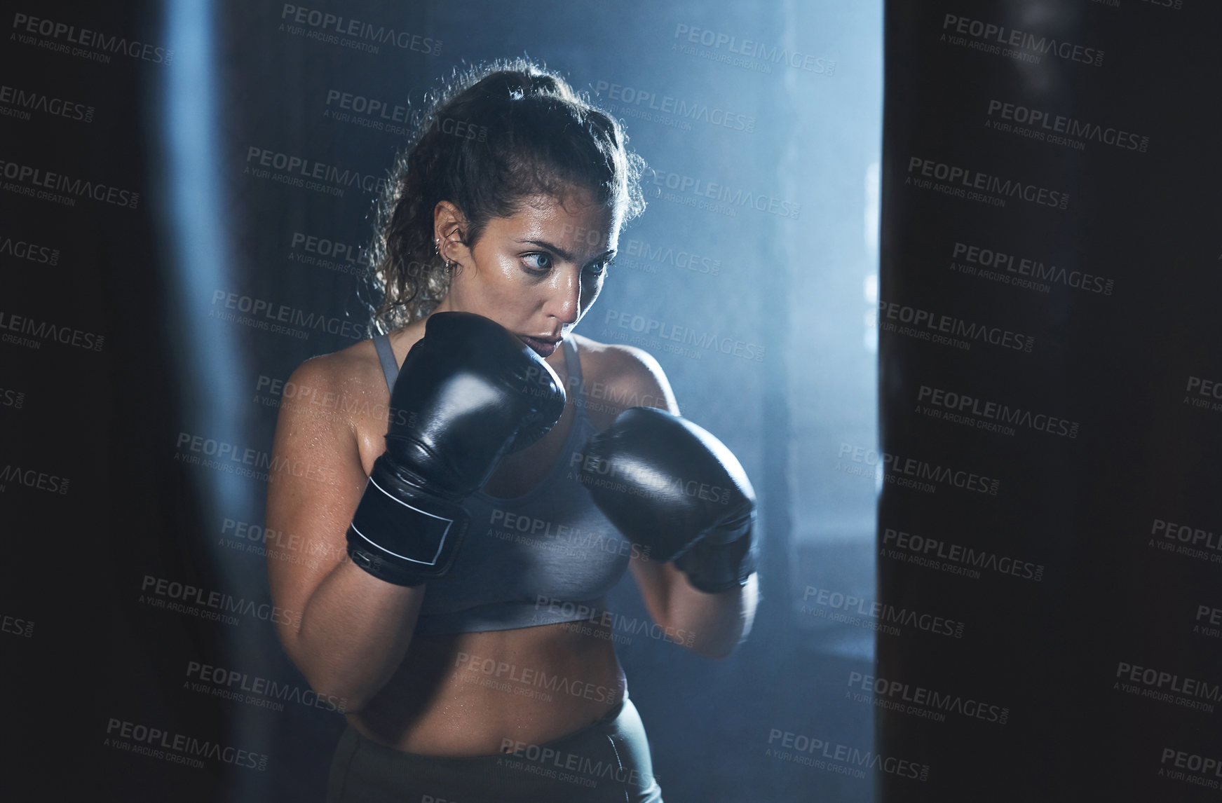 Buy stock photo Shot of a sporty young woman boxing in a gym