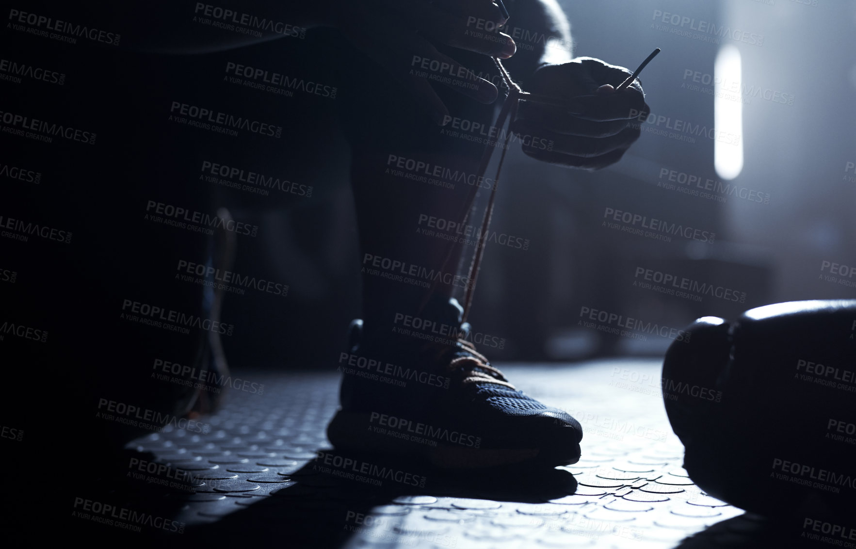 Buy stock photo Closeup shot of an unrecognisable man tying his laces in a gym