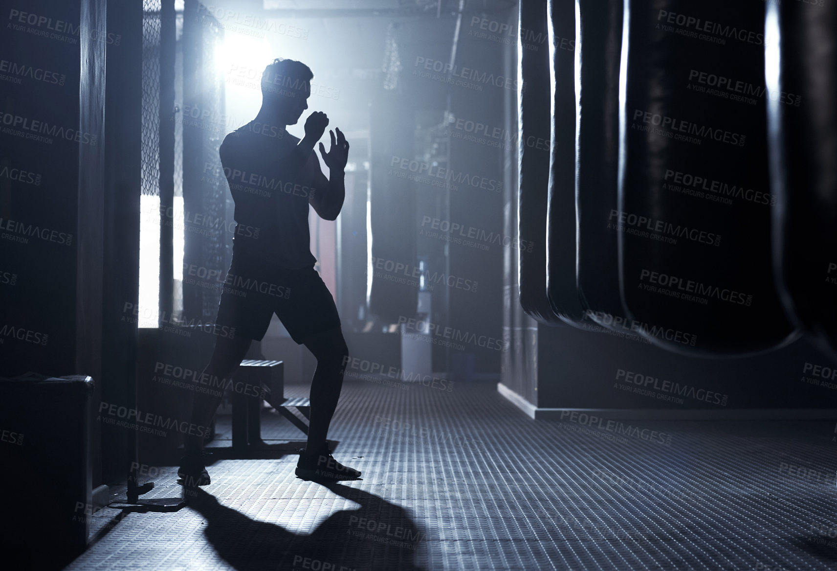 Buy stock photo Shot of a sporty young man kickboxing in a gym