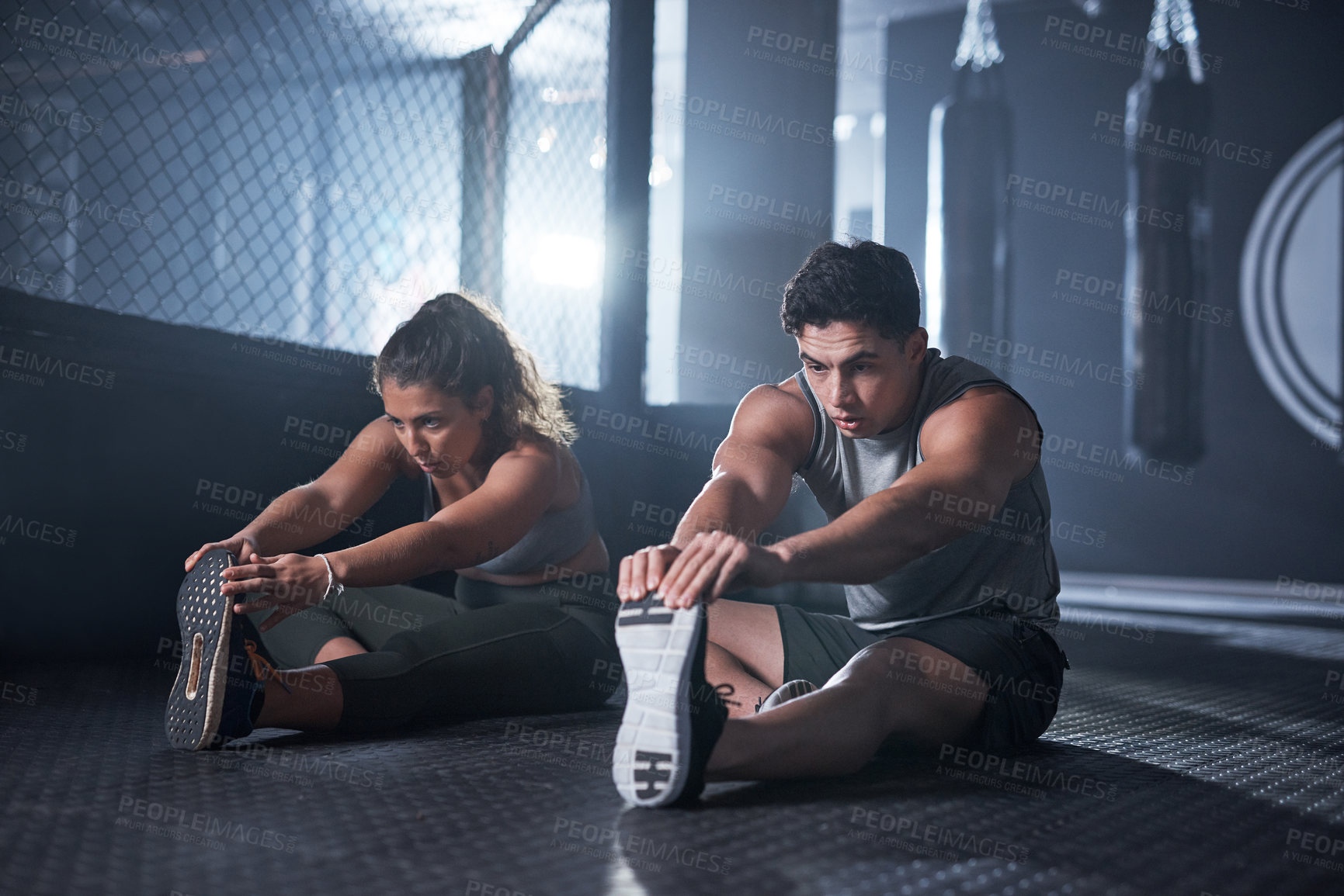 Buy stock photo Shot of two sporty young people exercising together in a gym