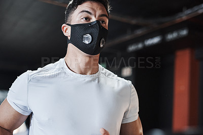Buy stock photo Cropped shot of a handsome and athletic young man wearing a mask while working out in the gym
