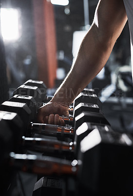 Buy stock photo Cropped shot of an unrecognizable male athlete grabbing a set of dumbbells during his workout in the gym