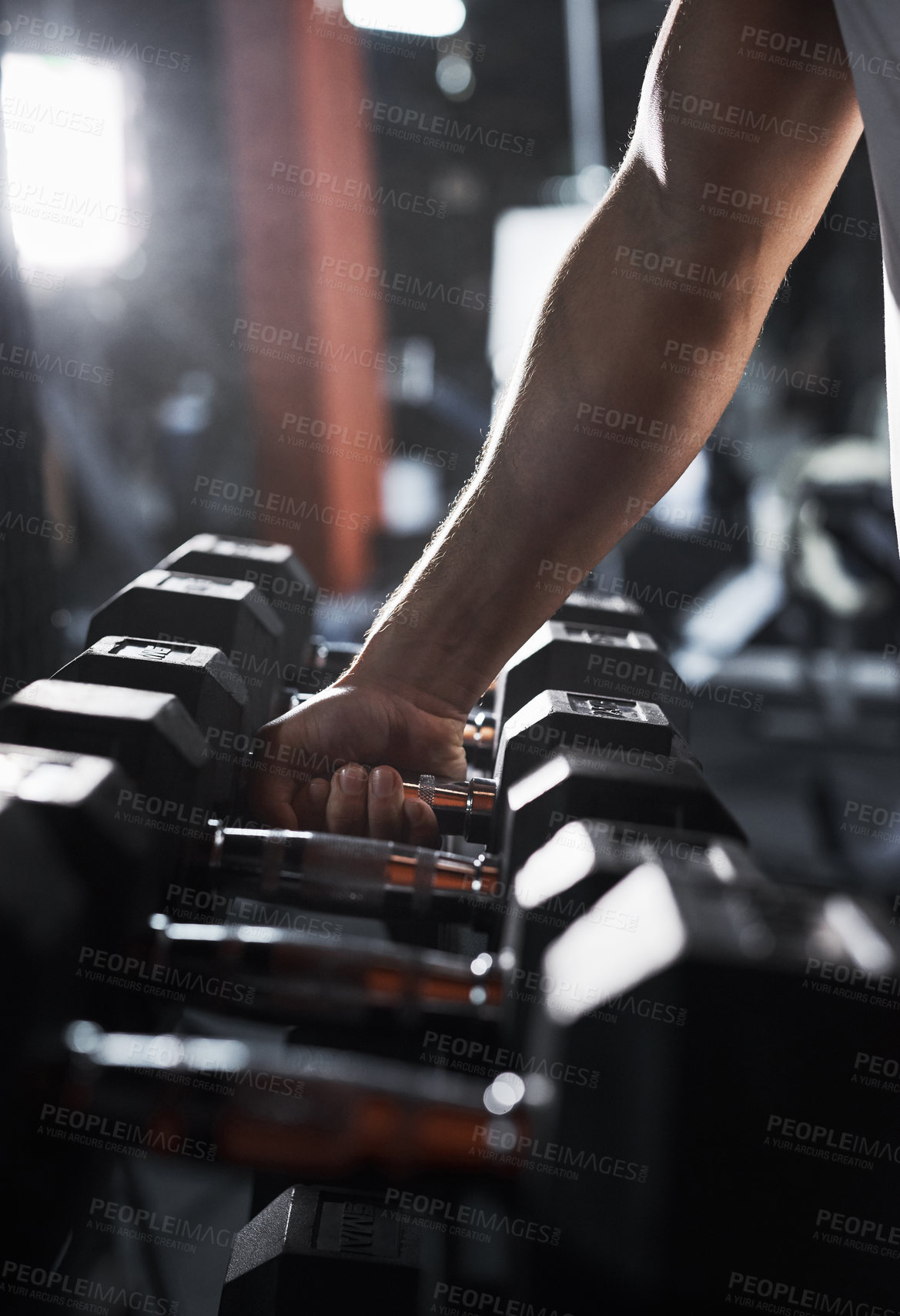 Buy stock photo Cropped shot of an unrecognizable male athlete grabbing a set of dumbbells during his workout in the gym