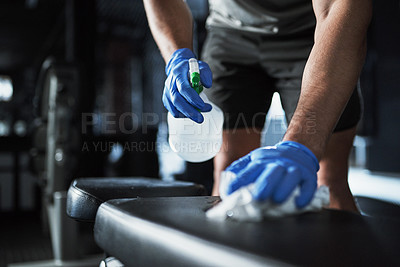 Buy stock photo Cropped shot of an unrecognisable man disinfecting the surfaces in a gym