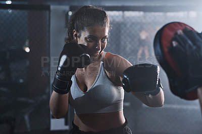 Buy stock photo Shot of a young woman practicing with her coach at a boxing gym