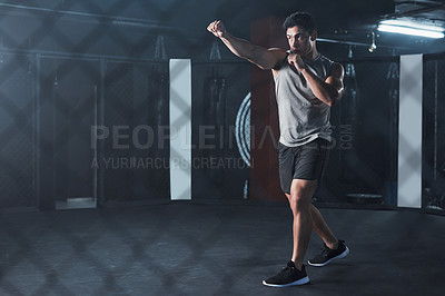 Buy stock photo Shot of a young man practicing his kickboxing routine at a gym