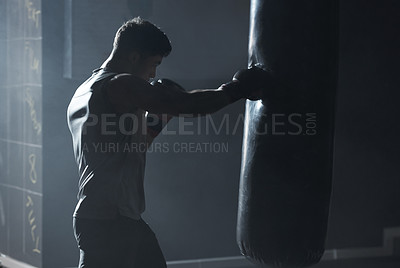 Buy stock photo Shot of a young man practicing his boxing routine at a gym