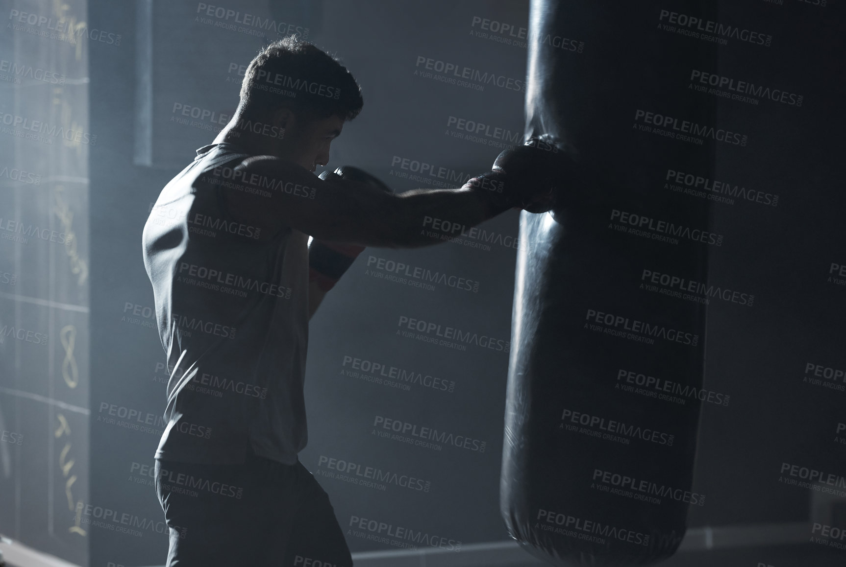 Buy stock photo Shot of a young man practicing his boxing routine at a gym