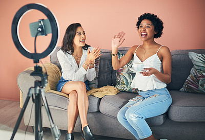 Buy stock photo Shot of two young women sitting together while recording a video for their blog at home