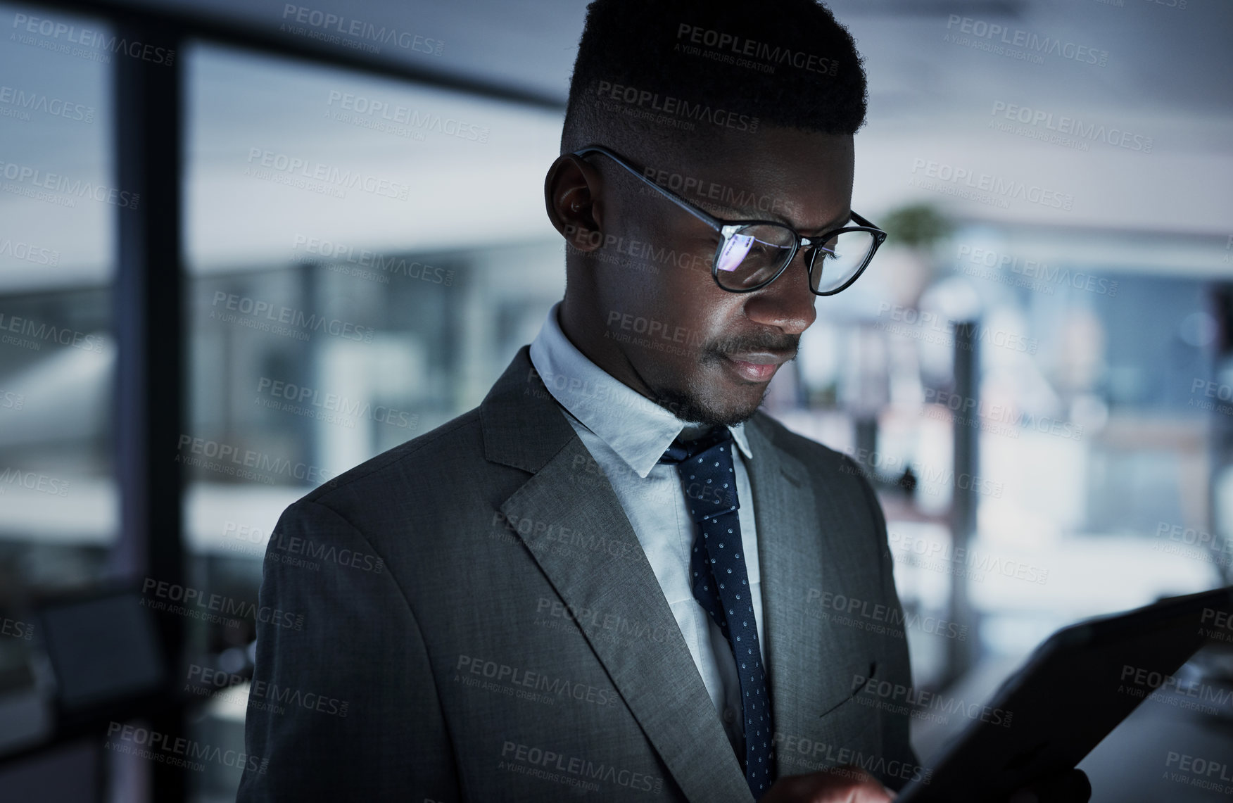 Buy stock photo Shot of a young businessman using a digital tablet in an office at night