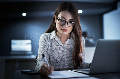 Buy stock photo Shot of a young businesswoman going through paperwork while working in an office at night