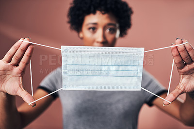 Buy stock photo Studio shot of a young woman holding up a mask