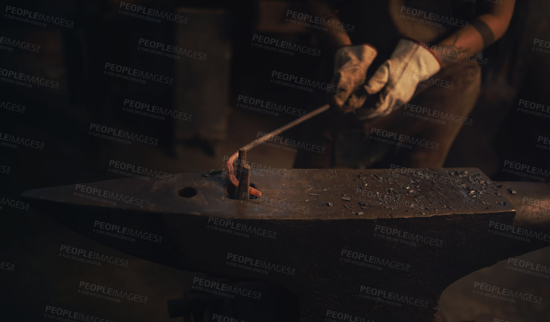 Buy stock photo Shot of a blacksmith working with a hot metal rod in a foundry