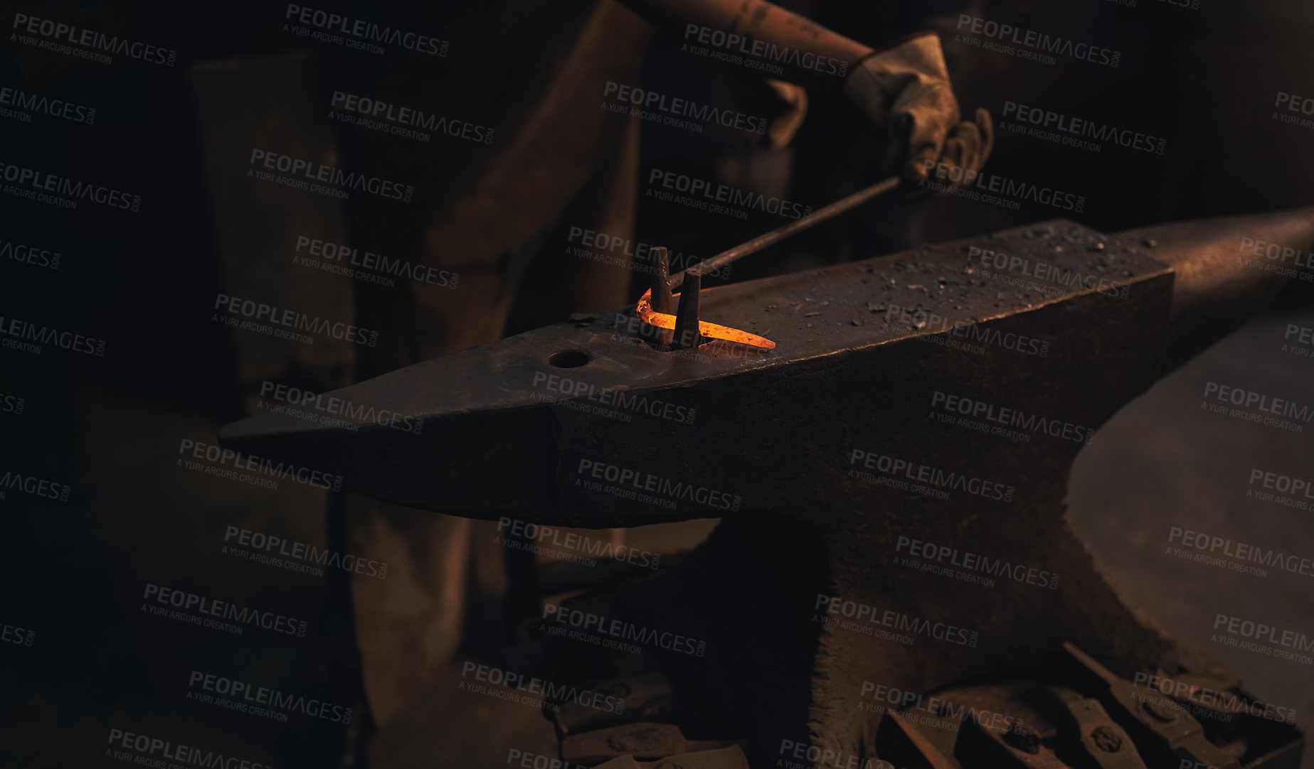 Buy stock photo Shot of a blacksmith working with a hot metal rod in a foundry