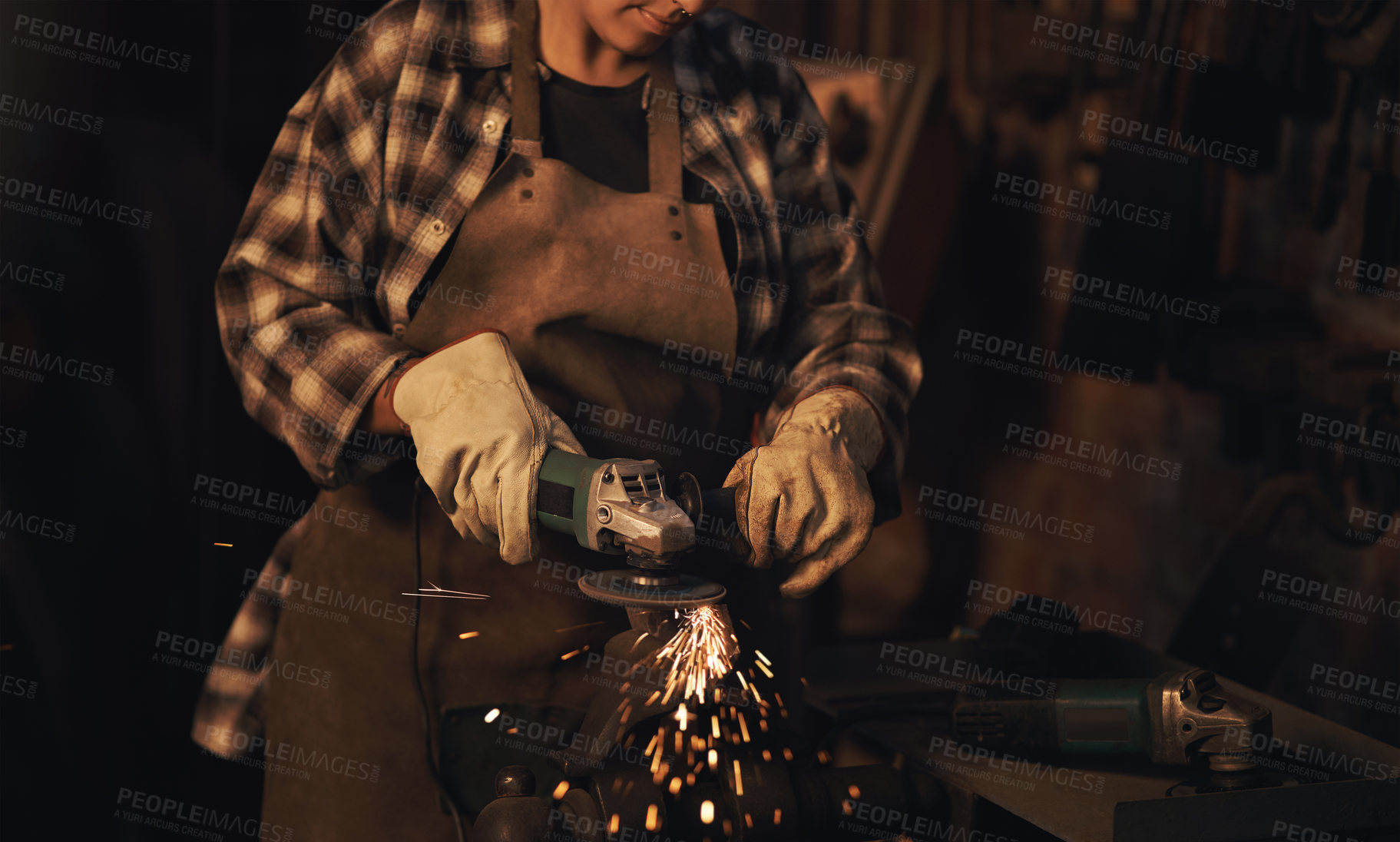 Buy stock photo Shot of a woman using an angle grinder while working at a foundry