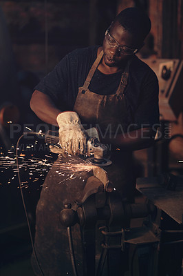 Buy stock photo Shot of a young man using an angle grinder while working at a foundry