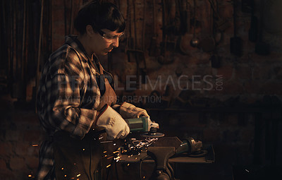 Buy stock photo Shot of a young woman using an angle grinder while working at a foundry