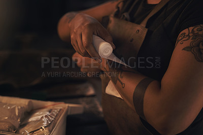 Buy stock photo Shot of a woman wrapping a bandage around her wrist while working at a foundry