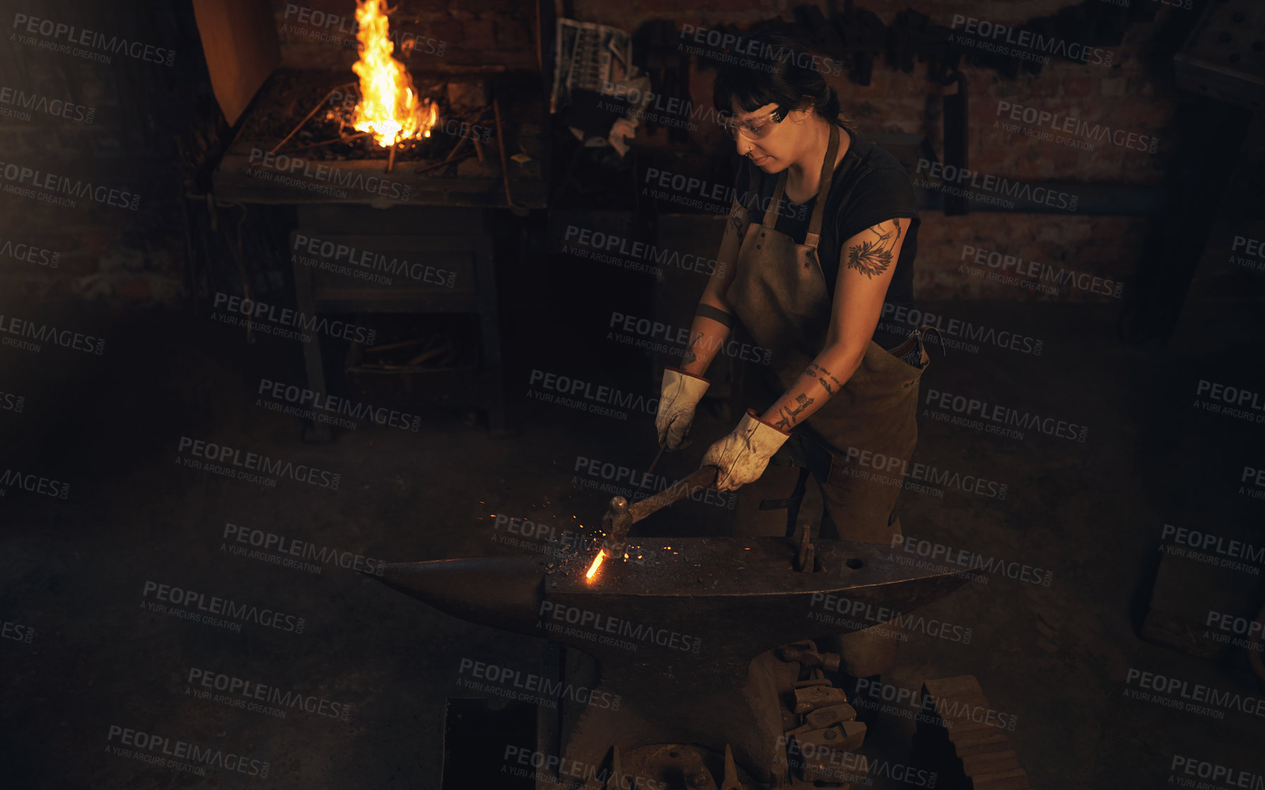 Buy stock photo Blacksmith, steel and hammer in workshop for craft, skill and artisanal creativity. Woman, manufacturing and hot iron in foundry for production, forging and shaping with safety gear in metal industry