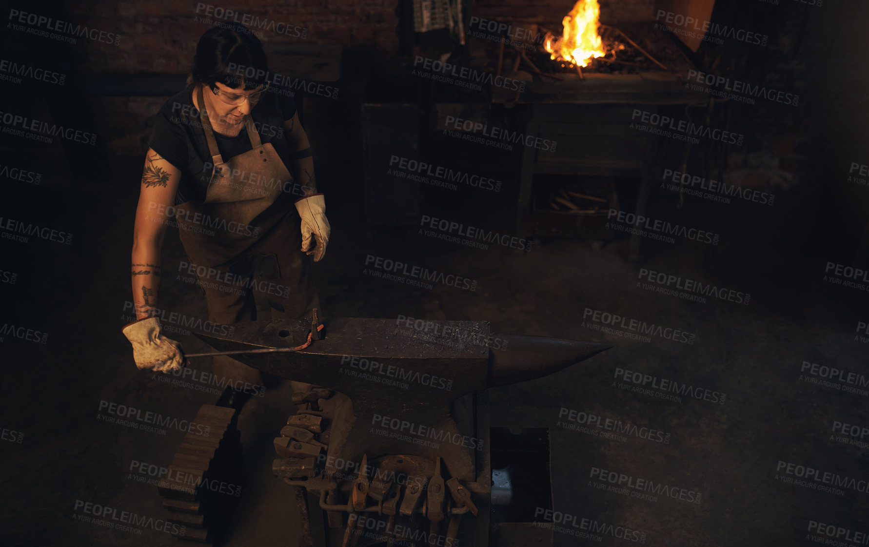 Buy stock photo Welding, tools and woman with steel, workshop and proud of gender equality in foundry or blacksmith. Hardworking, apron and manufacturing in factory, person or skills for welder and confident in dark