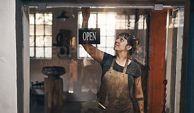 Buy stock photo Shot of a young woman hanging an open sign at the entrance of a foundry