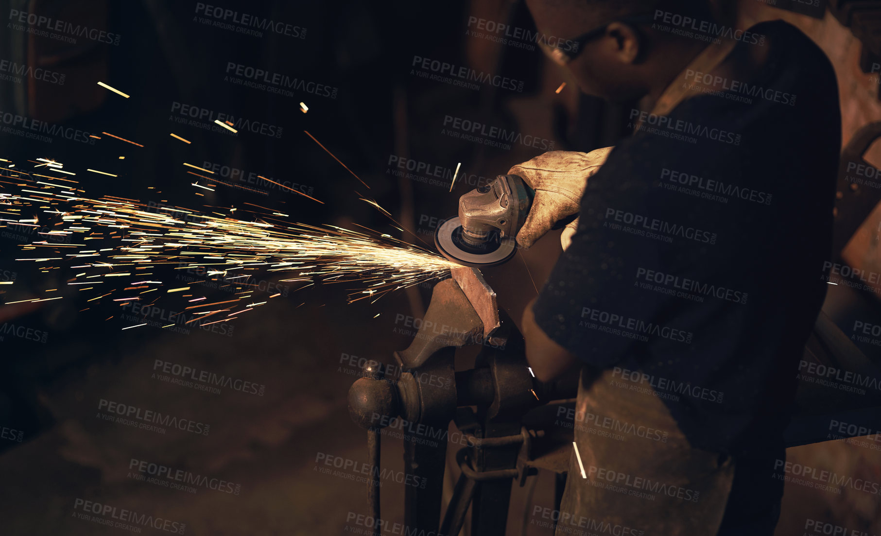 Buy stock photo Shot of a man using an angle grinder while working at a foundry
