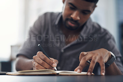 Buy stock photo Closeup shot of a young businessman writing in a notebook in an office