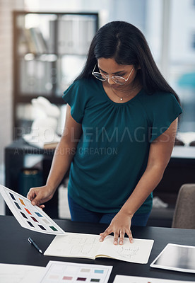 Buy stock photo Shot of a young designer working with sketches and colour swatches in an office
