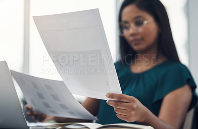 Buy stock photo Closeup shot of a young businesswoman going through paperwork in an office
