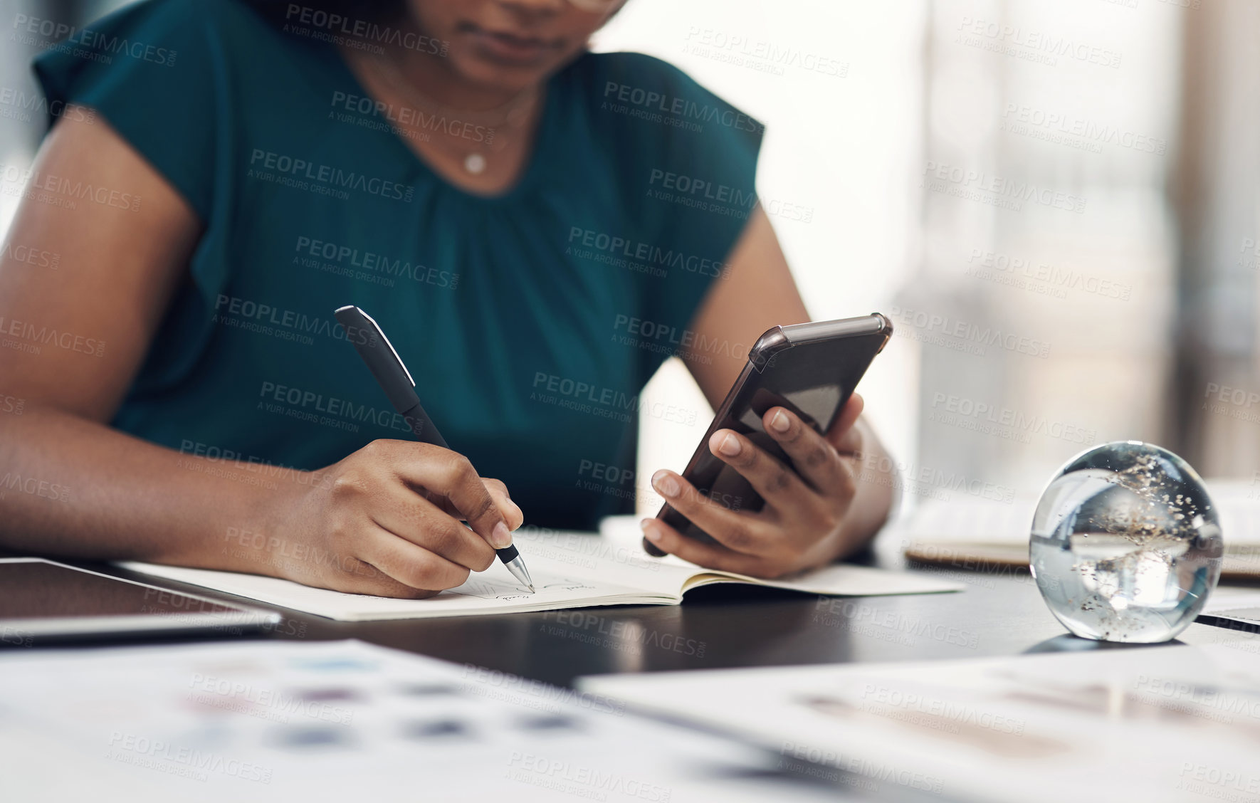 Buy stock photo Closeup shot of an unrecognisable designer writing notes while using a cellphone in an office