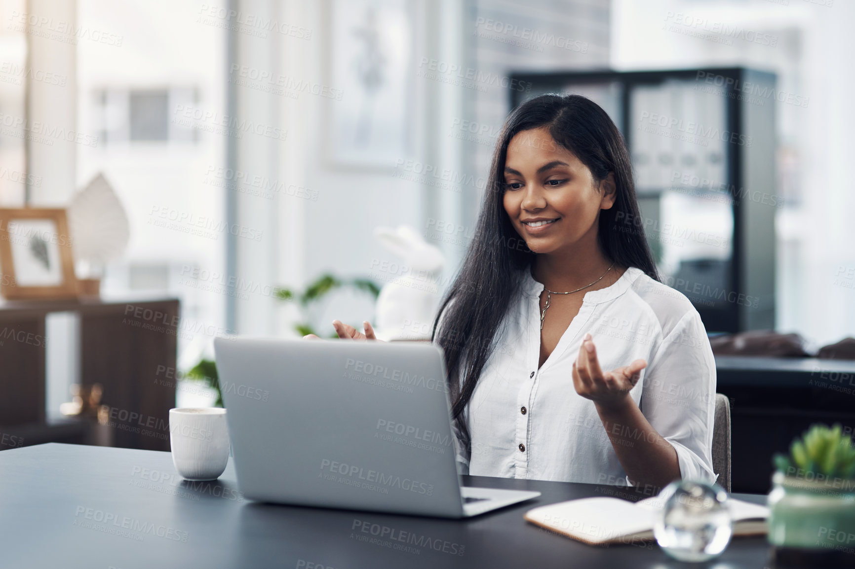 Buy stock photo Shot of a young businesswoman making a video call on a laptop in an office
