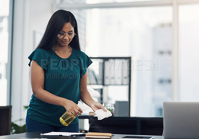 Buy stock photo Shot of a young businesswoman cleaning a workspace in an office