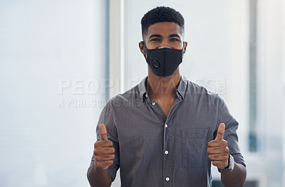 Buy stock photo Portrait of a young businessman wearing a face mask and showing thumbs up in an office