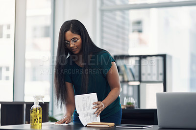 Buy stock photo Shot of a young businesswoman cleaning a workspace in an office
