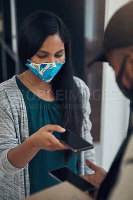 Buy stock photo Shot of a masked young man and woman using smartphones during a home delivery