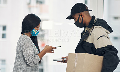 Buy stock photo Shot of a masked young man and woman using smartphones during a home delivery