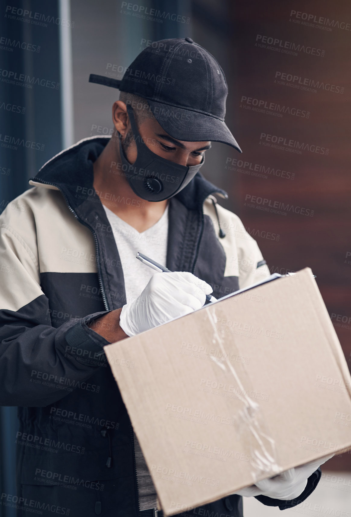 Buy stock photo Shot of a masked young man delivering a package to a place of residence