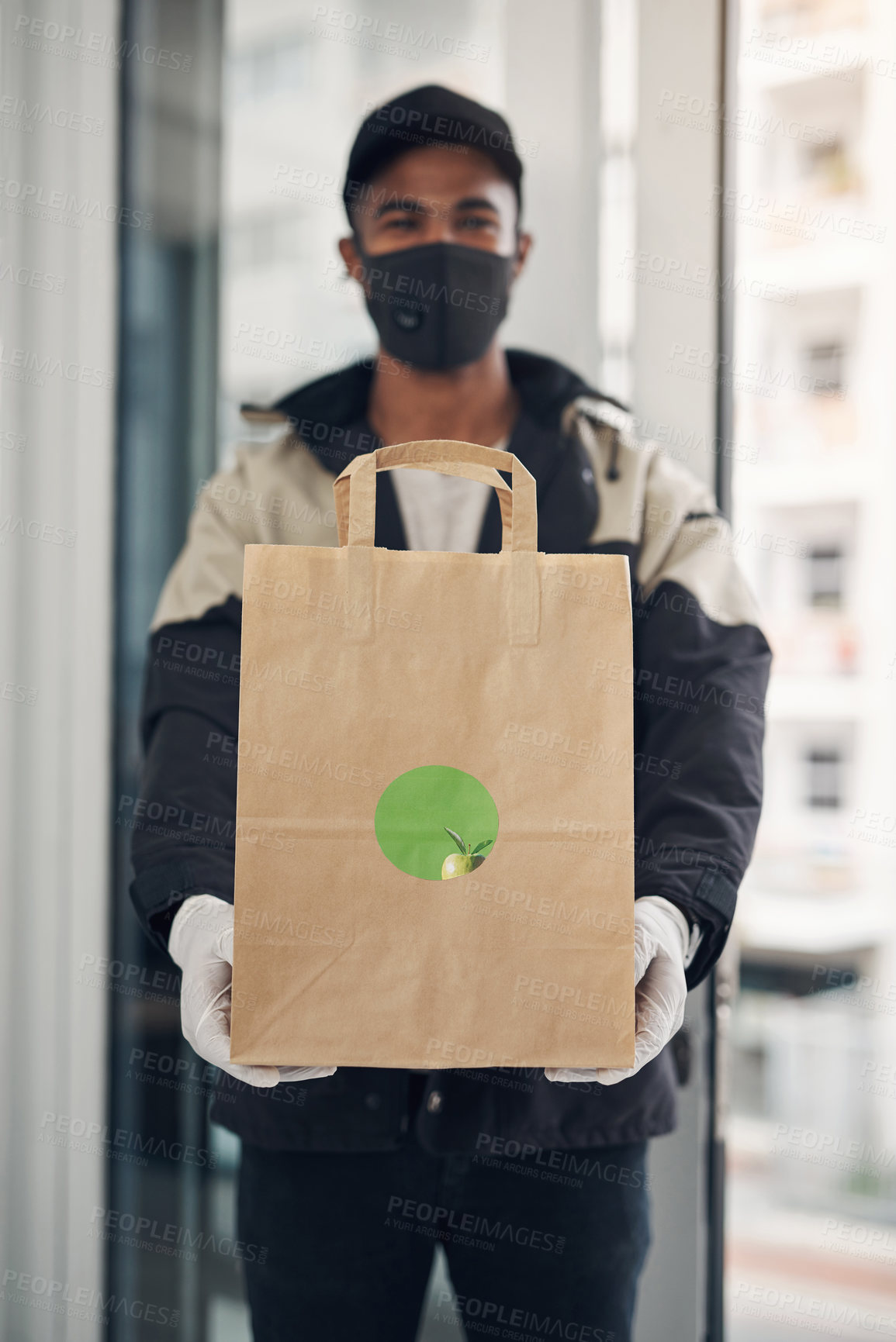 Buy stock photo Shot of a masked young man delivering takeout to a place of residence