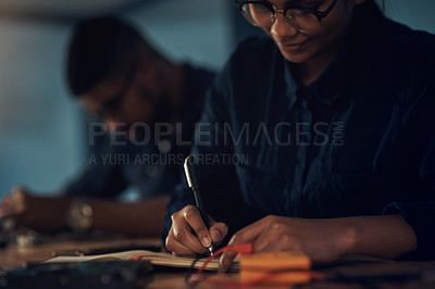 Buy stock photo Shot of a young technician writing in a notebook while repairing computer hardware