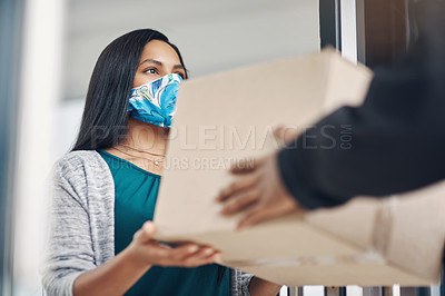 Buy stock photo Shot of a masked young woman receiving a delivery at home