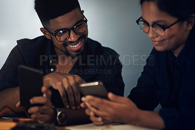 Buy stock photo Shot of two young technicians using their smartphone while repairing computer hardware